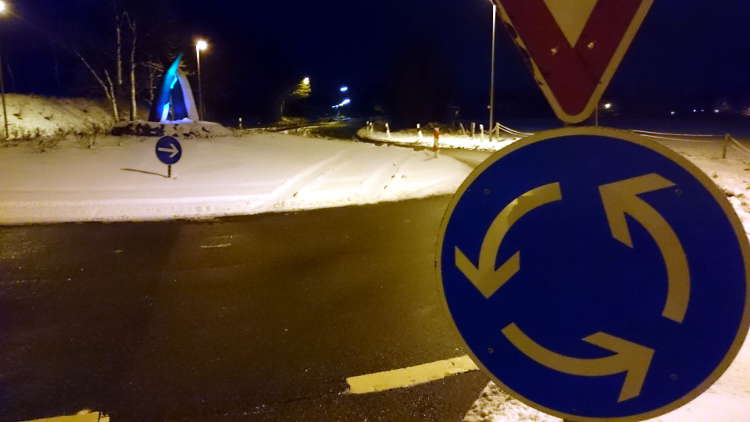 Kreisverkehr im Schnee mit Fahrzeugspuren über die Insel